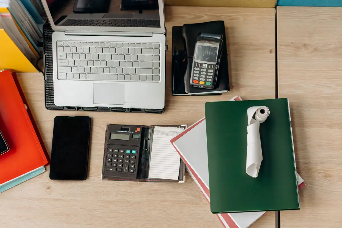 Birou cu laptop, terminal de plată, calculator și carnet pentru calculul CASS pe venituri extrasalariale