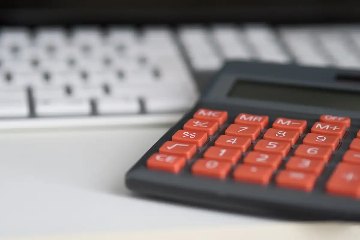 Calculator cu taste roșii așezat pe o tastatură albă, pentru calculele din formular