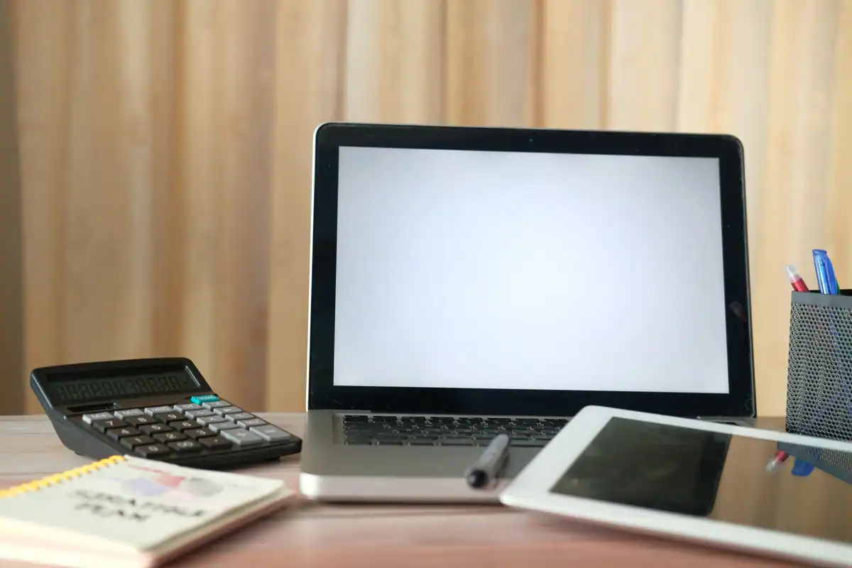 Birou cu laptop, calculator, tabletă și un carnet, pentru calculul impozitului pe salariu