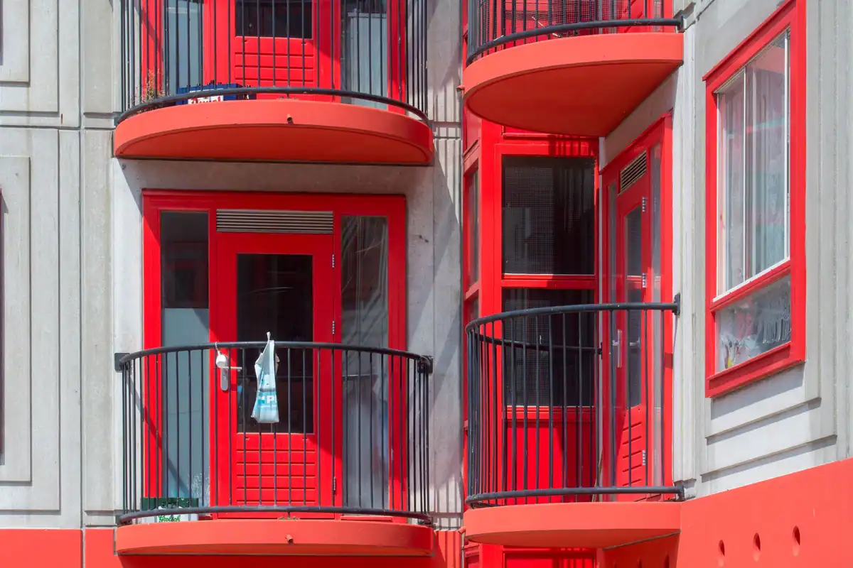 Balcoane roșii ale unui bloc modern, cu fațadă albă, pentru apartamente închiriate