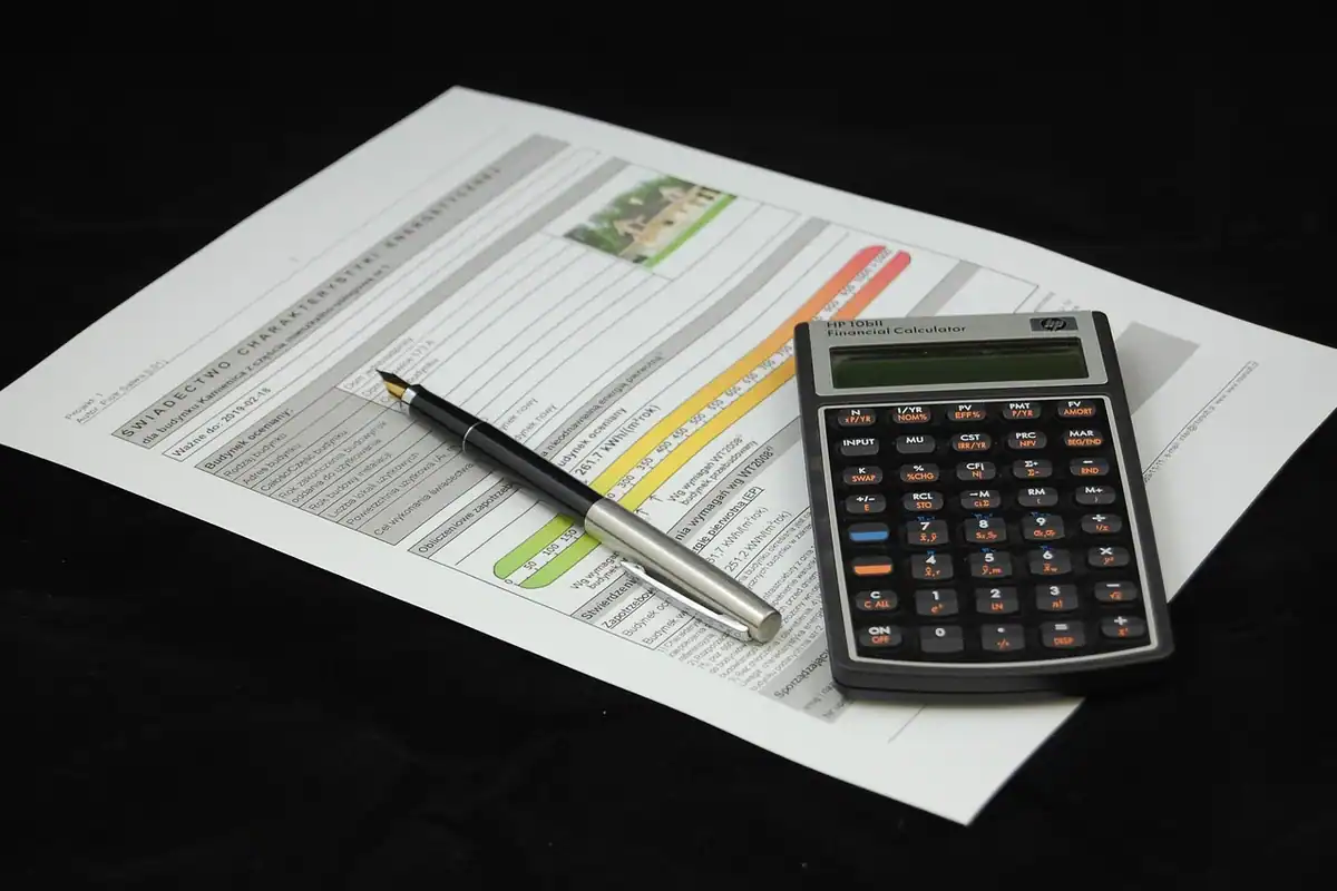 Calculator, pix și un formular completat, așezate pe masă, pentru calculul majorărilor