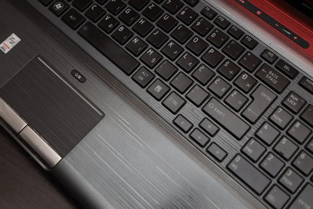 Tastatura unui laptop văzută de sus, cu touchpad metalic, pentru accesul în cont